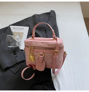 Detail of pink embossed bucket bag with floral bear patterns and golden padlock closure