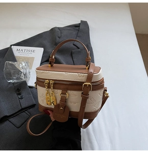 Detail of contrast color bucket bag with embossed floral pattern and metal hardware
