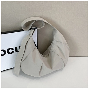 Detail view of the beige hobo bag showing pleated nylon fabric and wide shoulder strap