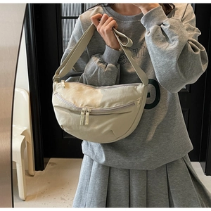 Detail of off-white crescent crossbody bag with double zippers and adjustable strap