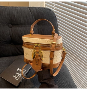 Detail of box-shaped crossbody bag featuring embossed floral patterns and golden hardware