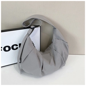 Detail of grey pleated crescent bag featuring textured nylon fabric and wide shoulder strap