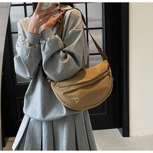 Detail view of khaki crescent shoulder bag with adjustable strap on a model