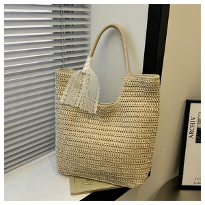 Detailaufnahme der beigen Stroh-Stofftasche mit eleganter weißer Spitzenschleife Dekor