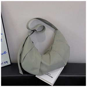 Detail showing the adjustable shoulder strap and smooth zipper on this green crescent bag