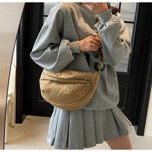 Detail of khaki nylon crescent bag showing the adjustable strap on a model outfit
