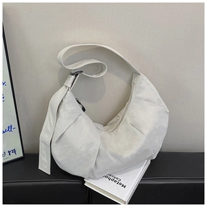 Detail of off-white crescent crossbody bag featuring pleated texture and wide strap