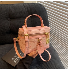 Detailed view of pink pebble-textured box bag with embossed bear and floral patterns