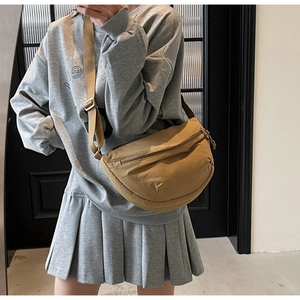 Khaki crescent moon bag with wide adjustable strap worn as a stylish crossbody bag