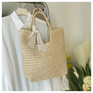 Detailaufnahme der gewebten Stroh-Tasche mit Textur und weißer Spitzenschleife Dekor