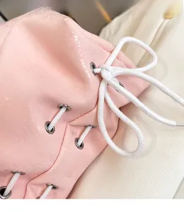 Dettaglio borsa rosa con texture marmorea e chiusura con coulisse a fiocco bianco