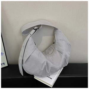 Detail of light gray nylon crescent bag with pleated texture and adjustable wide strap