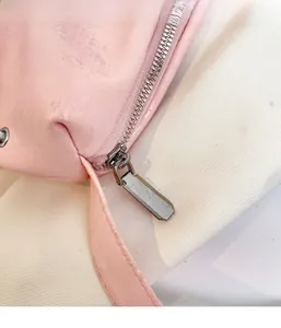 Dettaglio di una borsa glitterata rosa con cerniera in metallo e finitura lucida