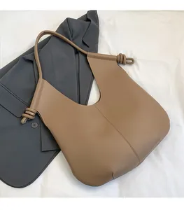 Detail of knot design on shoulder strap of a large brown matte leather bucket bag