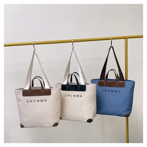 Detail of canvas and denim tote bags with leather trim and ZHCNMA logo lettering