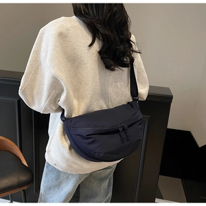 Detail of navy blue crescent crossbody bag worn by model showing size and nylon fabric