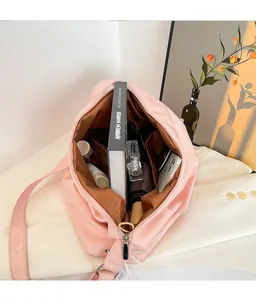Vista interna della spaziosa borsa tote rosa con libri, ombrello e vari cosmetici