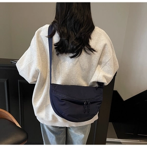 Detailed back view of a dark blue nylon crescent bag worn as a crossbody on model