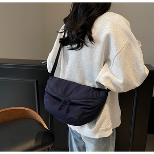 Detail of navy blue crescent nylon bag featuring double zip closure and woven strap