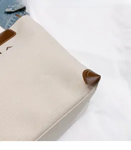 Detail of canvas tote bag with reinforced brown leather corners and white stitching
