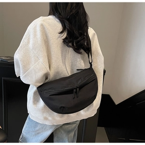 Rear view of a black crescent nylon crossbody bag worn on a casual gray sweatshirt