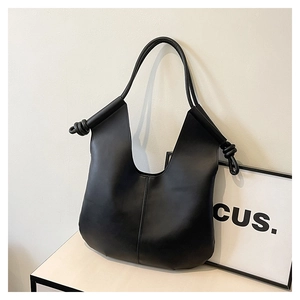 Minimalist black leather tote bag with unique V-shaped opening and knotted strap detail