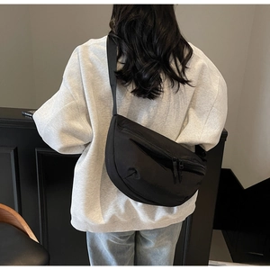 Detail showing the adjustable wide strap and smooth nylon texture of the crescent bag
