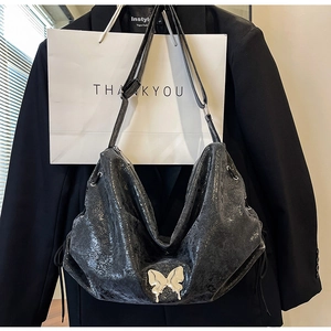 Dettaglio della borsa tote vintage nera con farfalla argentata e coulisse laterale