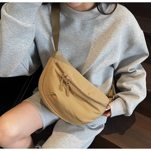 Khaki canvas crescent bag on model showing adjustable strap and double metal zippers
