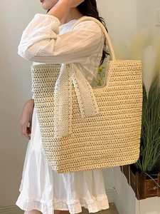 Große handgewebte Strohtasche mit Spitzenschleife in einem hellen, minimalistischen Raum