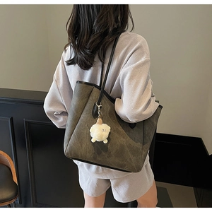 Große olivgrüne Shopper-Tasche mit weißem Plüsch-Schaf-Anhänger an der Schulter
