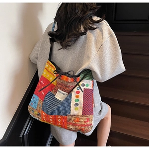 Close-up of ethnic style canvas tote bag with vibrant patchwork patterns and side ribbon