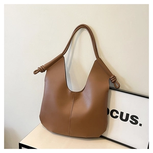 Detail of a brown leather Hobo bag featuring a unique spiral knot handle design on the side