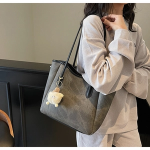 Detail der dunkelgrauen Shopper-Tasche mit schwarzen Riemen und weißem Schaf-Anhänger