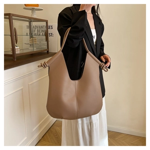 Detailed view of the knotted shoulder strap on a brown leather minimalist tote bag