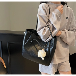 Detailansicht der großen schwarzen Leder-Tote-Bag mit süßem weißem Plüsch-Schaf-Anhänger