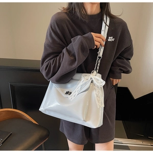 Detail der glänzenden Lackleder-Tasche mit Spitzenschleife und Kettenriemen