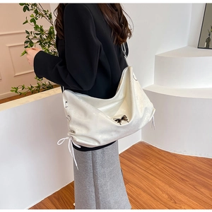 Dettaglio di una grande borsa bianca morbida con fiocco nero e lacci decorativi laterali