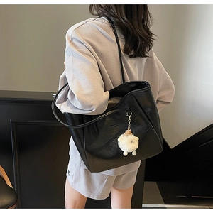 Schwarze Tote-Tasche aus PU-Leder mit flauschigem Lamm-Anhänger am Frauenmodell