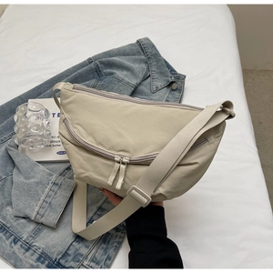 Macro view of beige nylon crescent bag with adjustable strap and zipper details