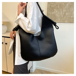 Detail of minimalist black hobo bag with a stylish knot handle and matte leather finish