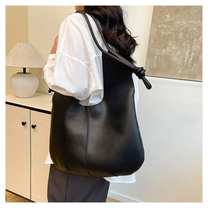 Detail of knotted shoulder strap and side seam on black hobo bag for modern commuting