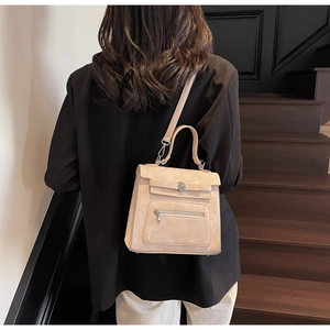 Chic beige crossbody bag with metal buckle and zipper pocket shown on model's shoulder