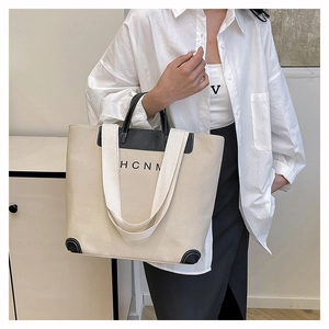 Detail of canvas tote bag with black leather reinforced corners and HCNM logo