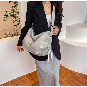 Dettaglio della borsa tote argento metallizzato con decoro a farfalla e coulisse laterali