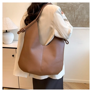 Detail of a large brown leather hobo shoulder bag with a unique knot strap design