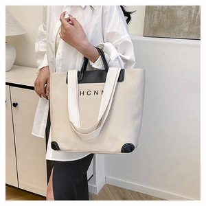 Close-up of beige canvas tote bag with black leather edges and HCNN artistic logo