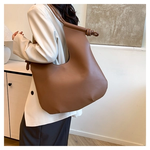 Detail of the caramel brown large capacity hobo bag with knotted strap on model's shoulder