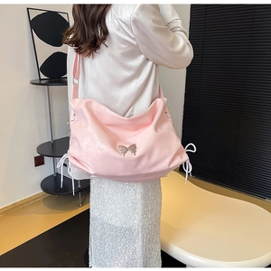 Dettaglio della borsa rosa con farfalla d'argento e coulisse laterali indossata da modella
