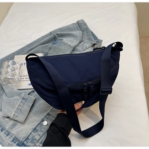 Detailed top view of a navy nylon crescent bag with double front zippers on denim fabric